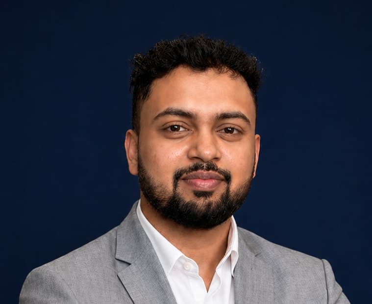 Portrait of Shubham in a grey blazer against a navy backdrop